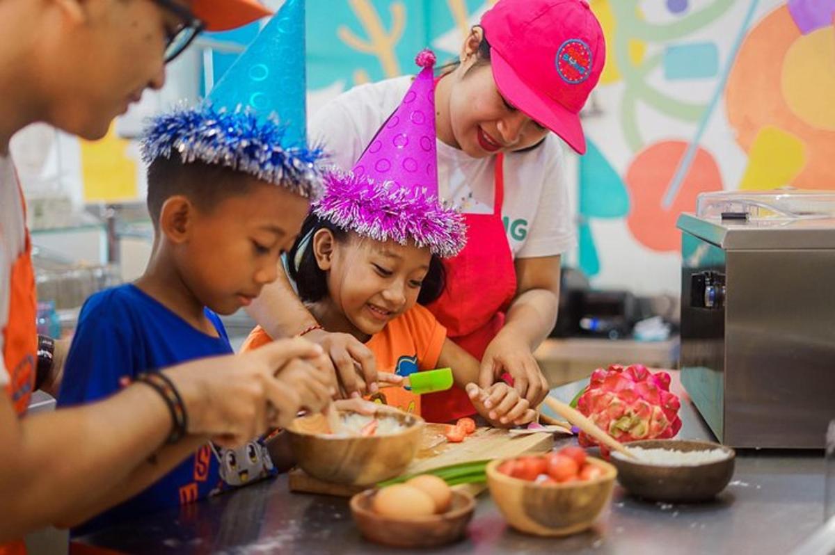 deux enfants et une femme préparant de la nourriture dans une cuisine