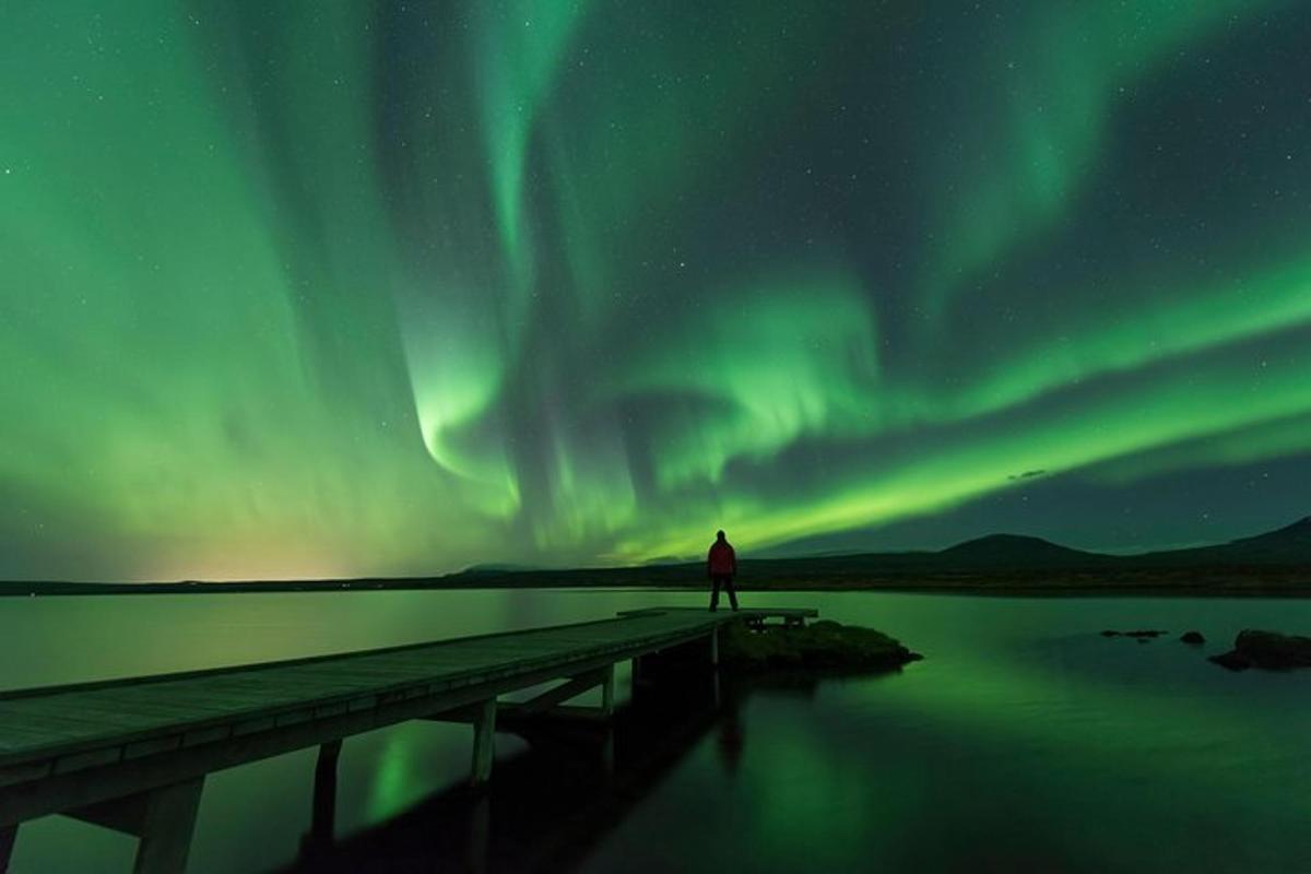 maður stendur á bryggju og horfir á norðurljósin