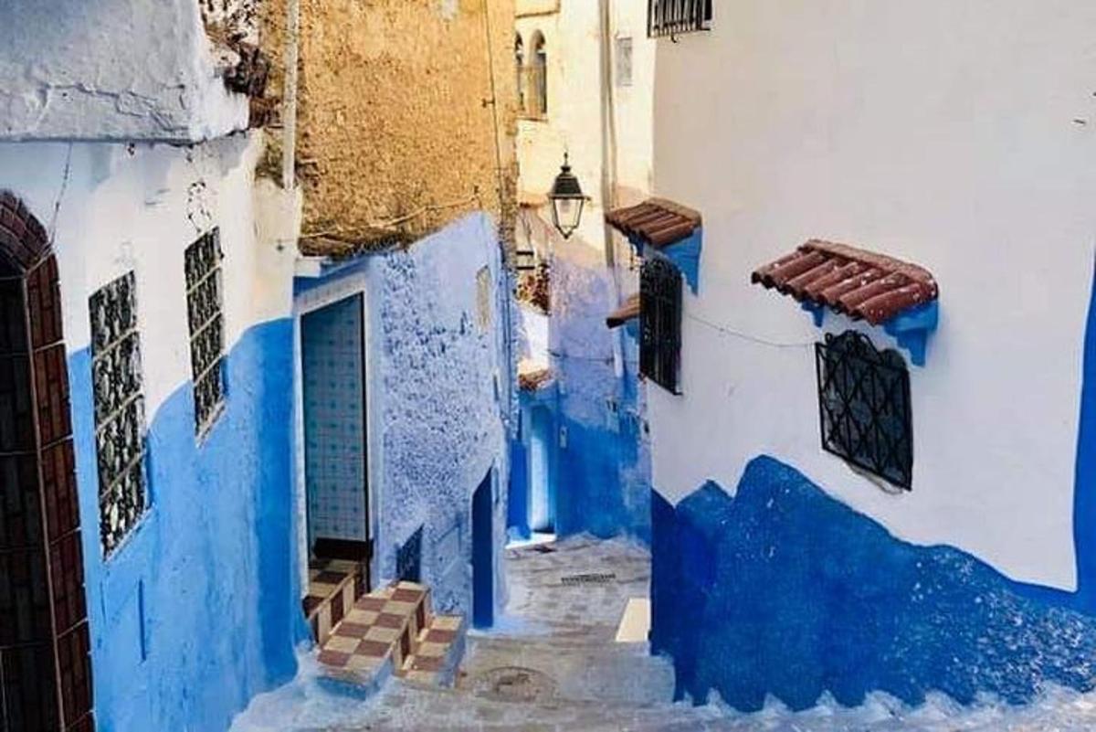 un carreró amb parets blaves i blanques i una porta