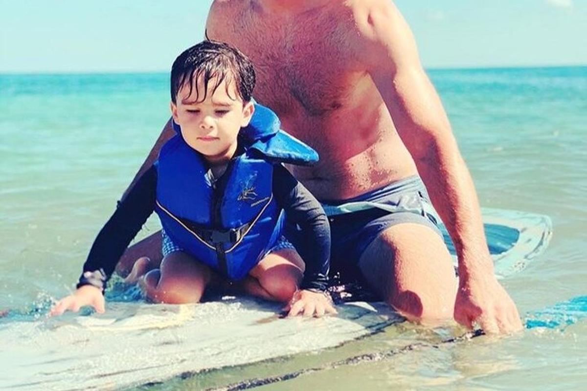 a man and a boy on a surfboard in the water