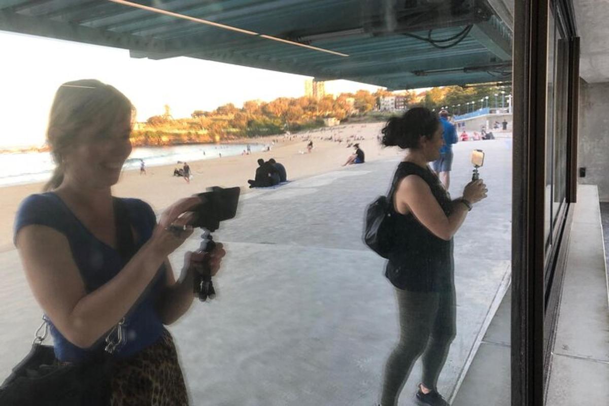 two women are taking pictures of the beach