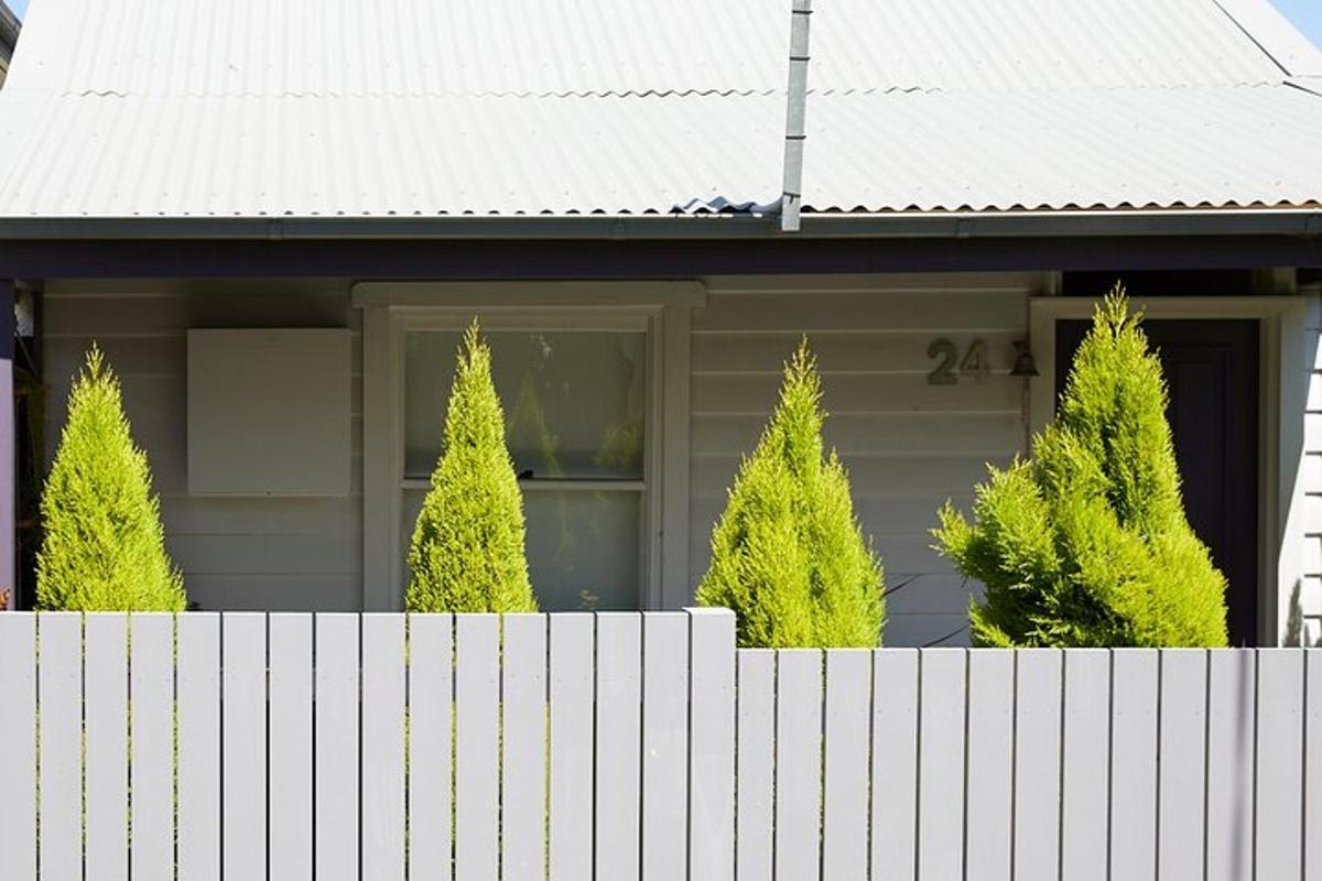 sebuah rumah dengan pagar dan pokok di hadapannya
