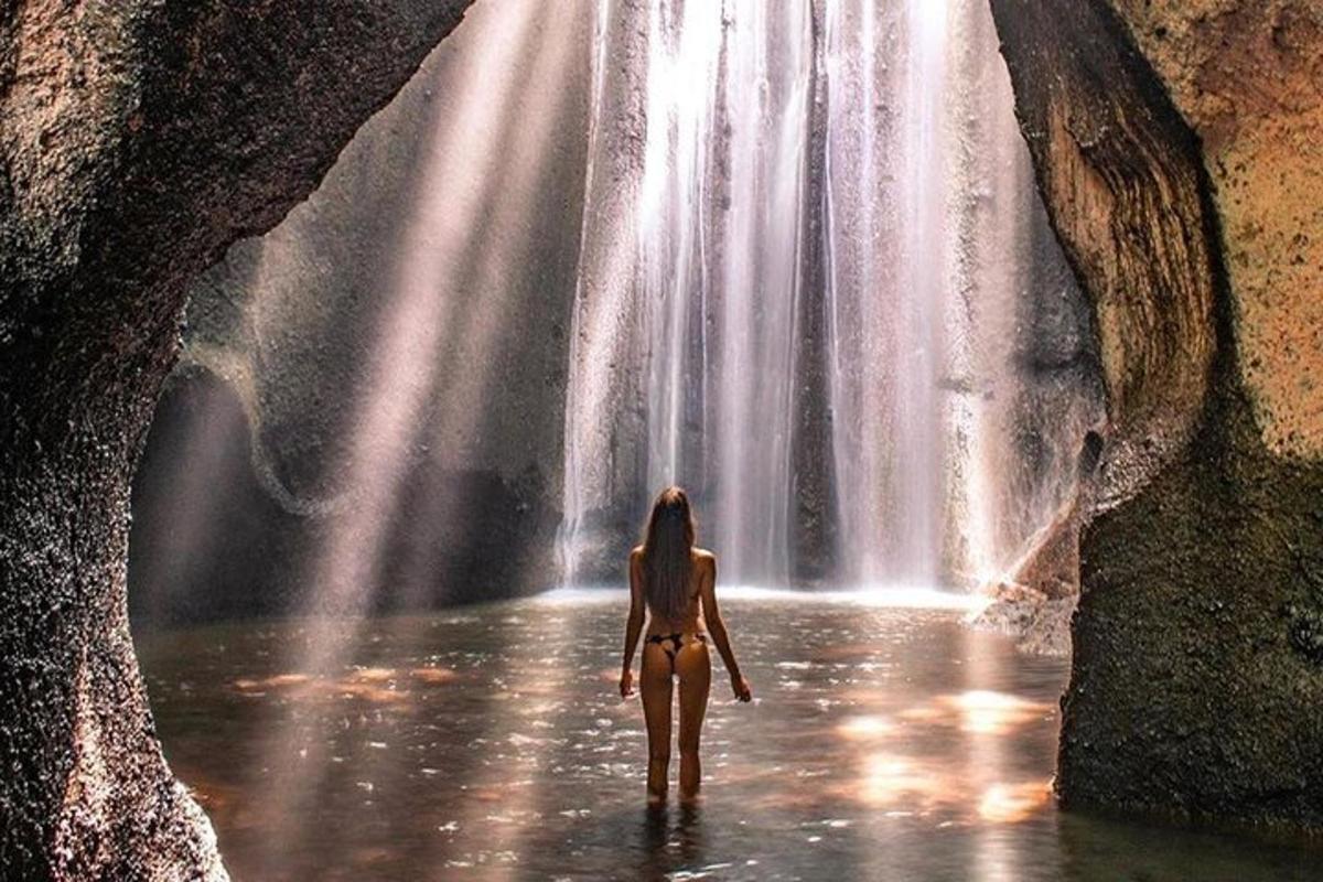 una donna che cammina nell'acqua davanti a una cascata