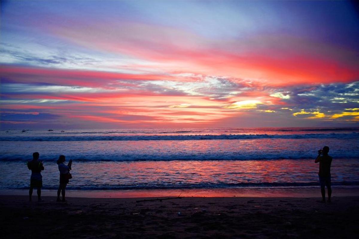 tre persone in piedi sulla spiaggia a guardare il tramonto