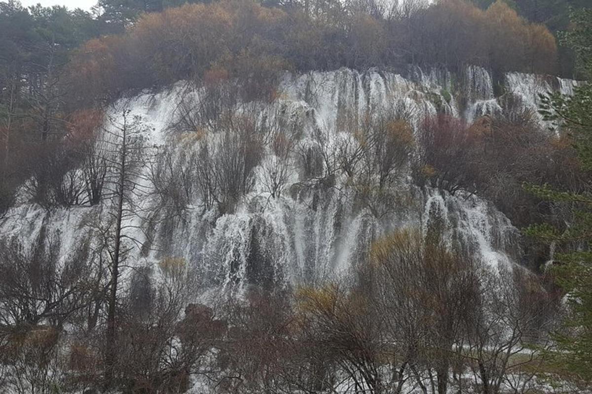 uma cachoeira na encosta de uma montanha com árvores