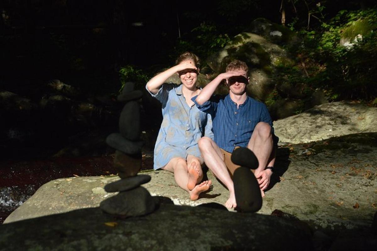 two men and a woman sitting on a rock
