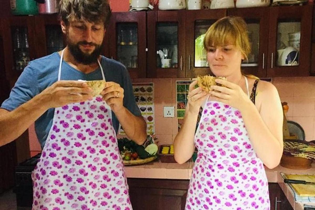 a man and a woman eating sandwiches in a kitchen