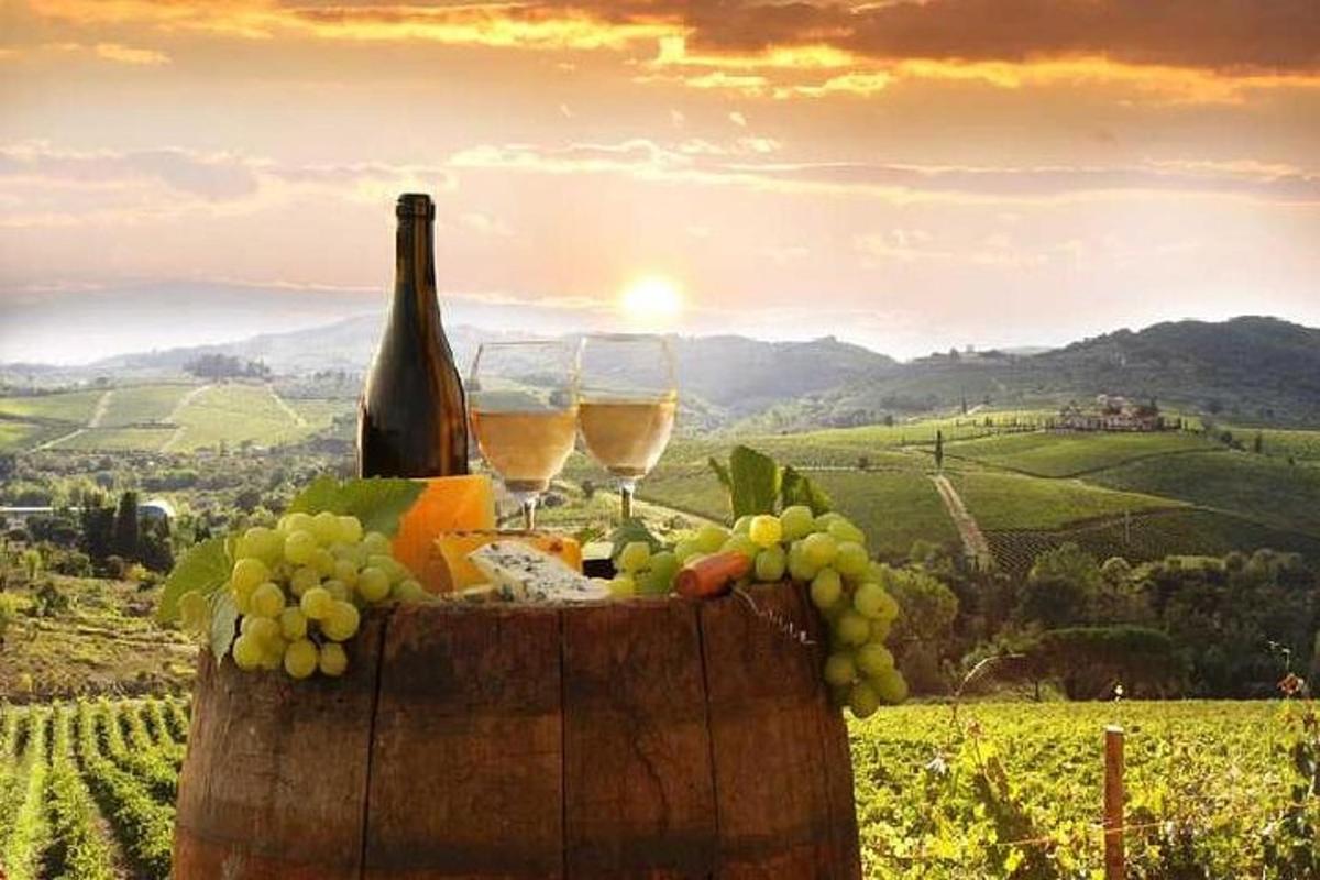 Un barril con copas de vino y uvas en una colina