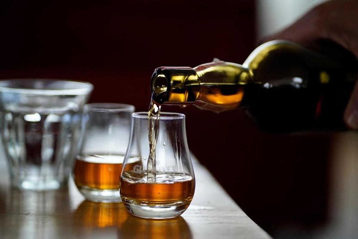 ένα άτομο που ρίχνει αλκοόλ σε ένα ποτήρι σε ένα τραπέζι