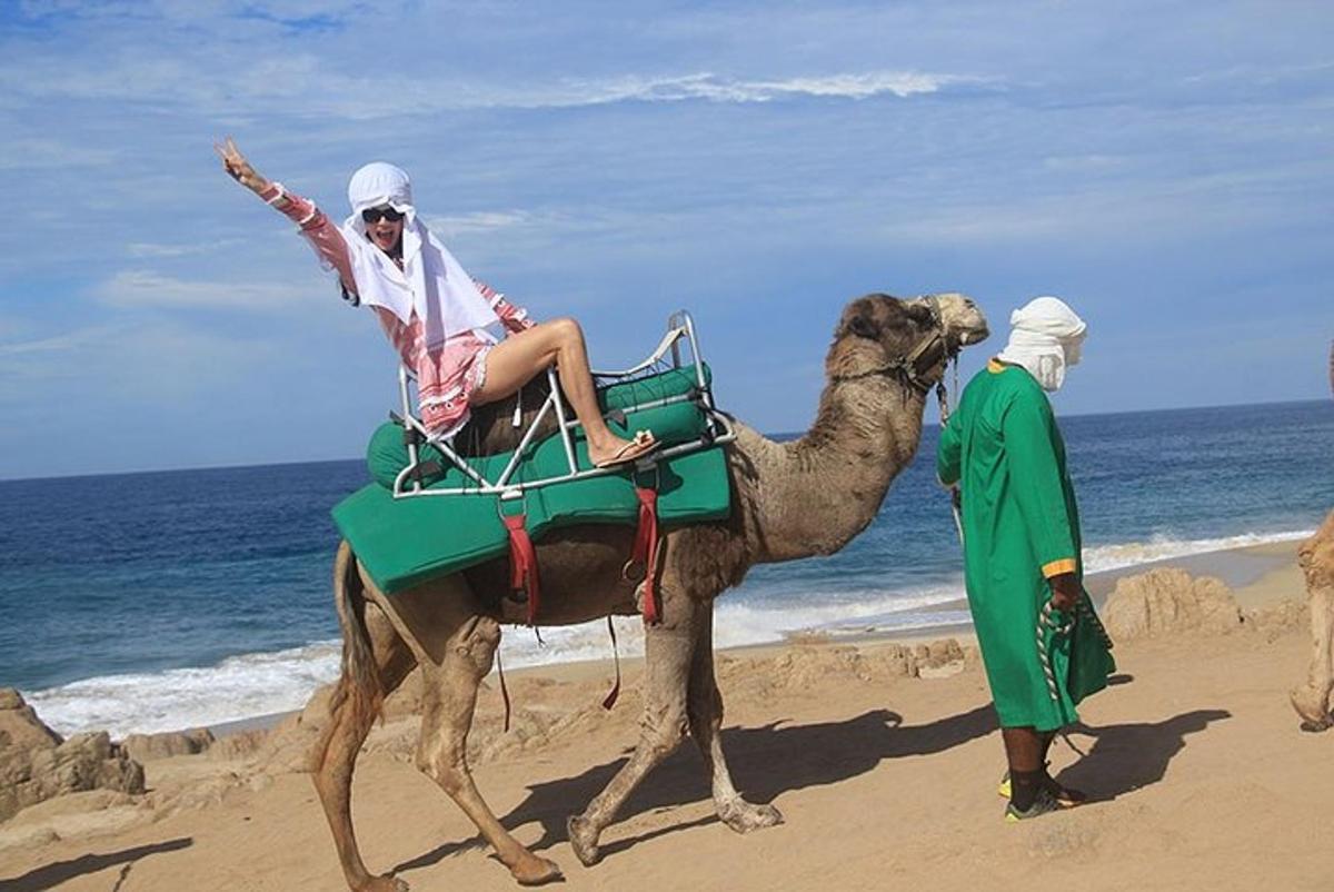 eine Person, die auf einem Kamel am Strand reitet
