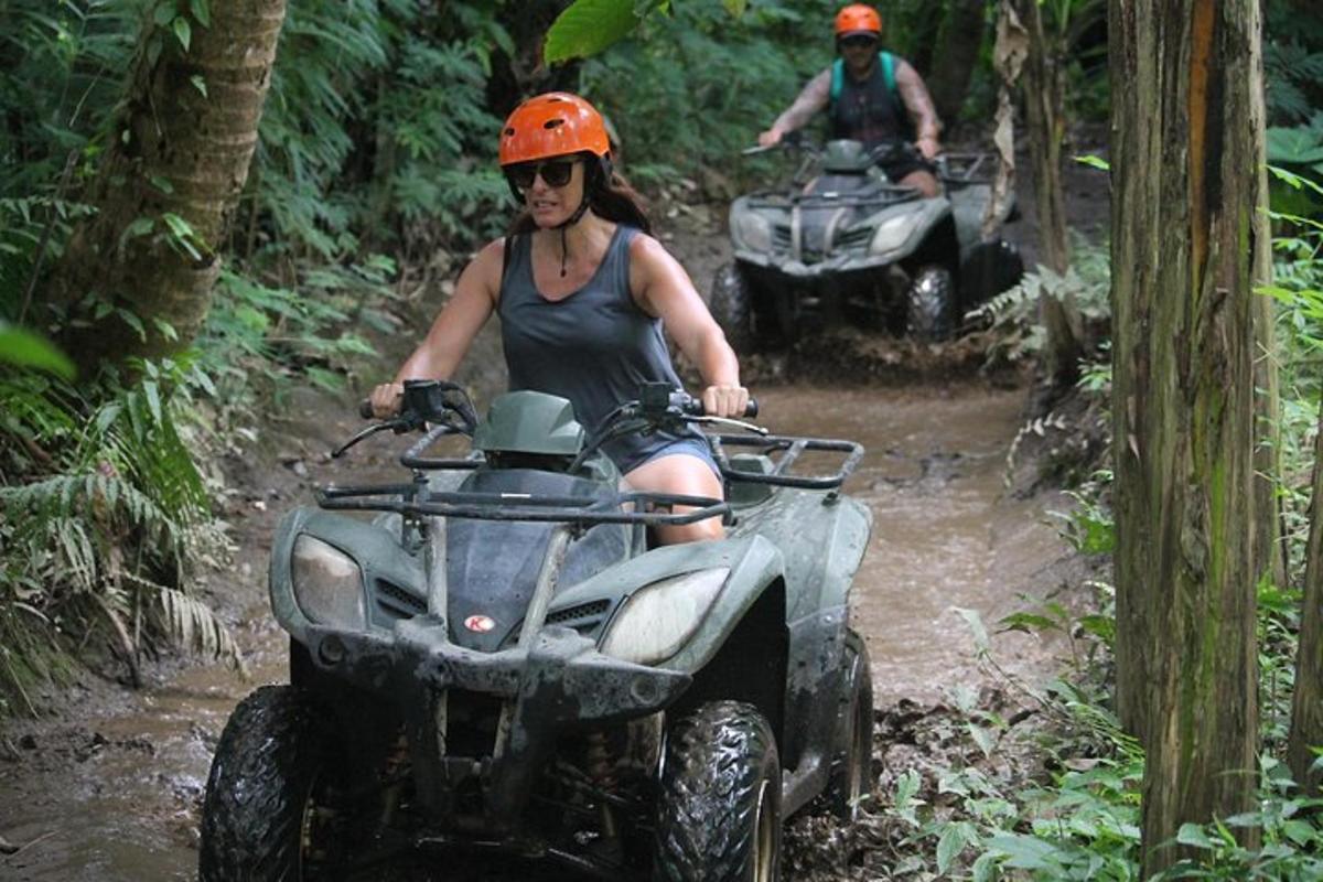 duas pessoas andando de quadriciclo em uma trilha de terra