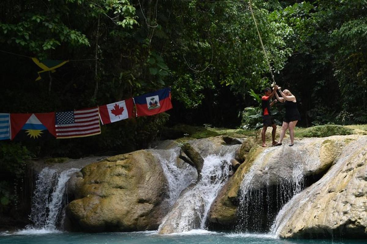 two people are standing on rocks in a waterfall