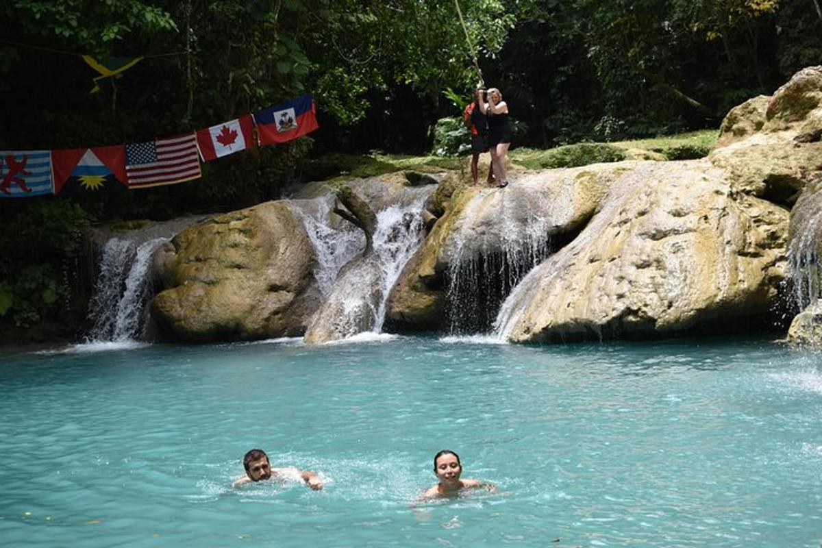 two people swimming in a pool in front of a waterfall