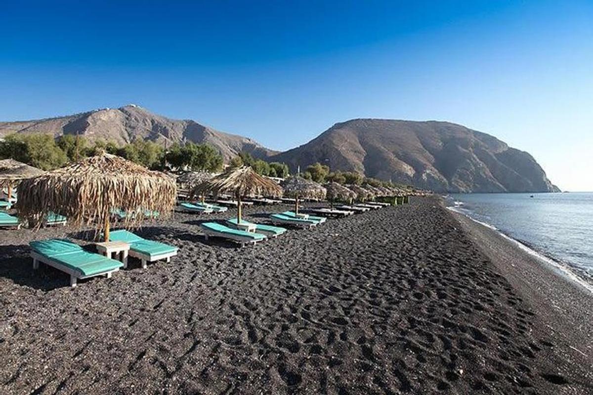 una platja amb cadires i para-sols de palla i l'aigua