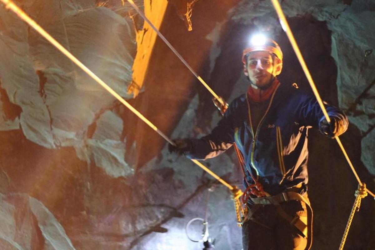 a man is holding ropes in a cave
