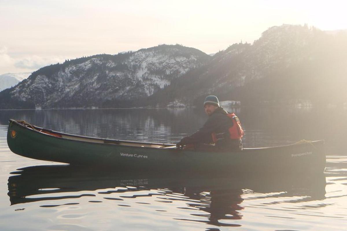 a man is sitting in a canoe on the water