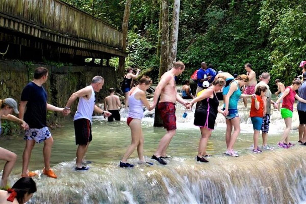 Un grupo de personas de pie frente a una cascada.