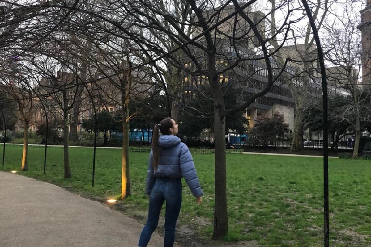a woman standing next to a tree in a park
