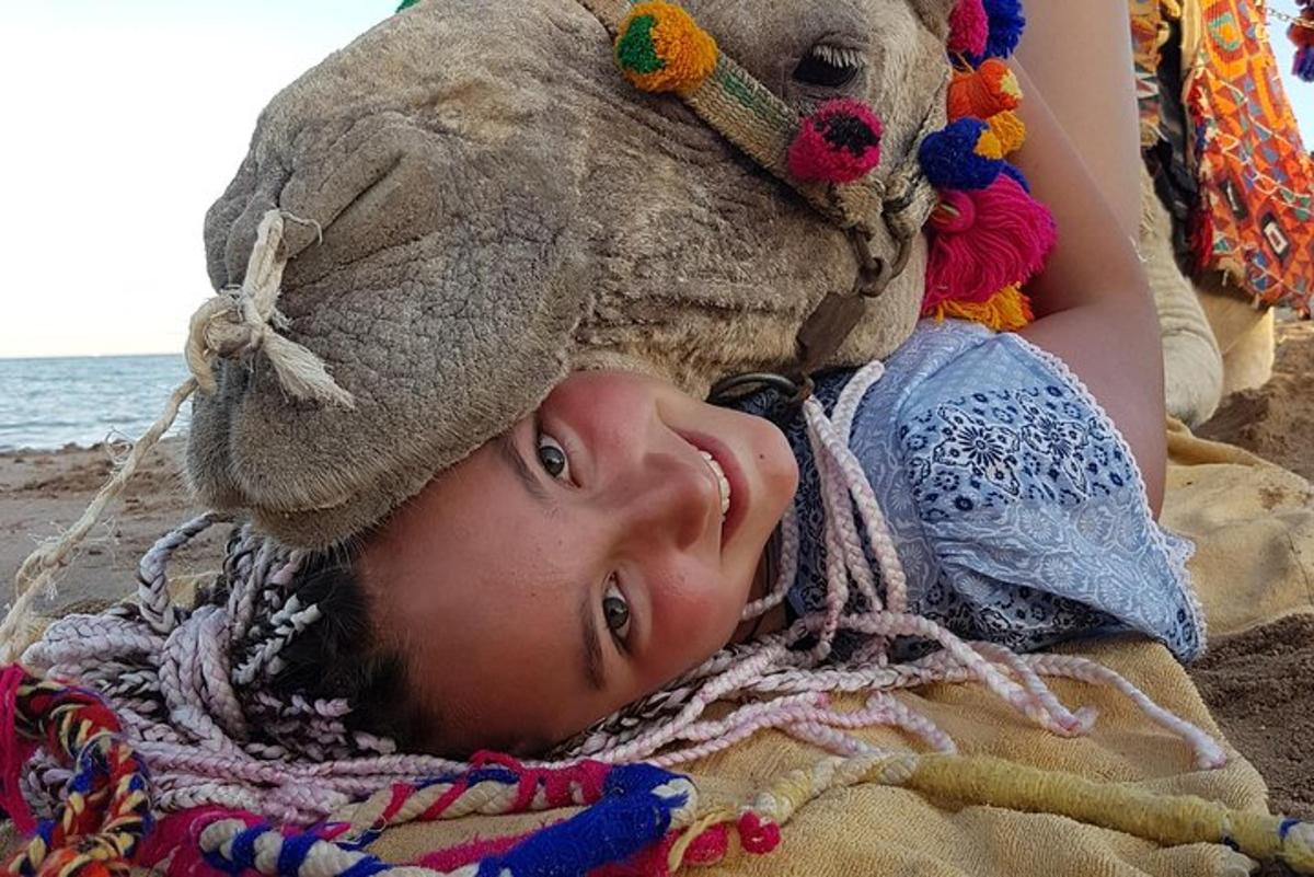 uma jovem deitada na praia com um bicho de pelúcia na cabeça