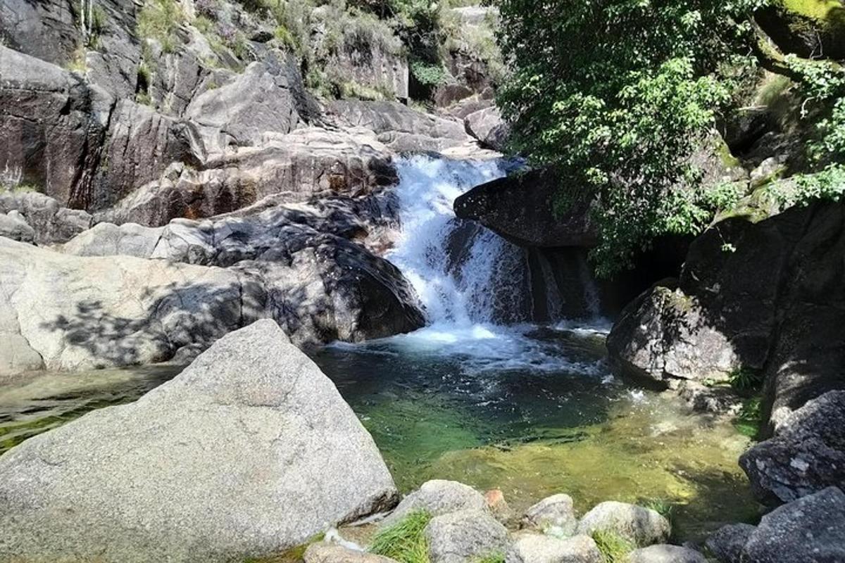 a waterfall on a rocky hill with a pool of water
