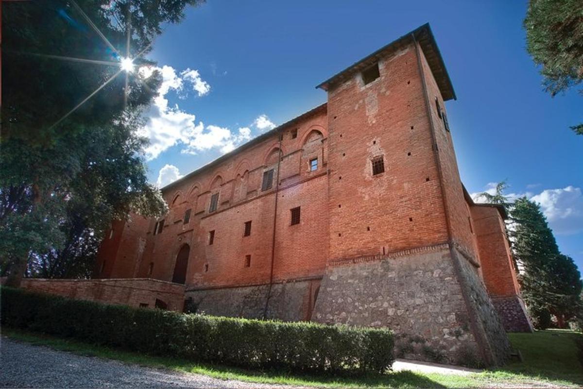 ein großes rotes Backsteingebäude mit der Sonne dahinter