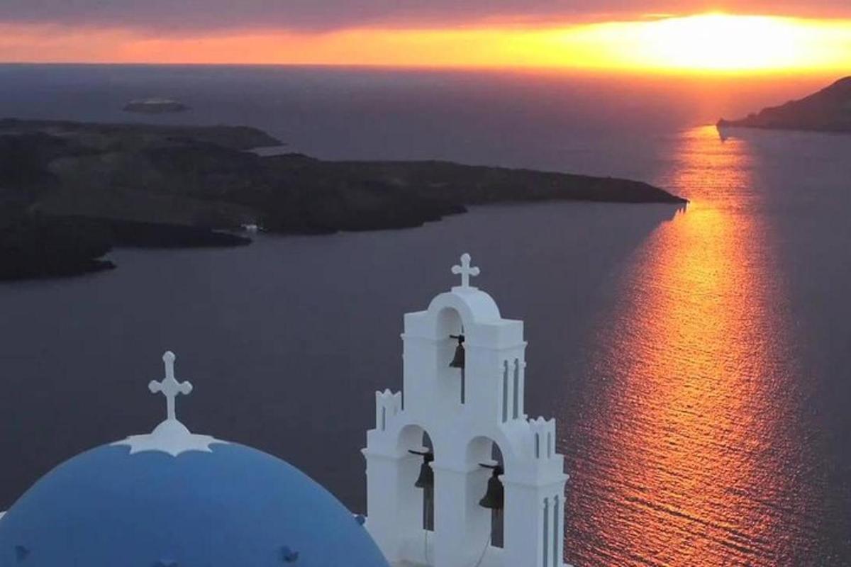 μια λευκή εκκλησία με φόντο ένα ηλιοβασίλεμα