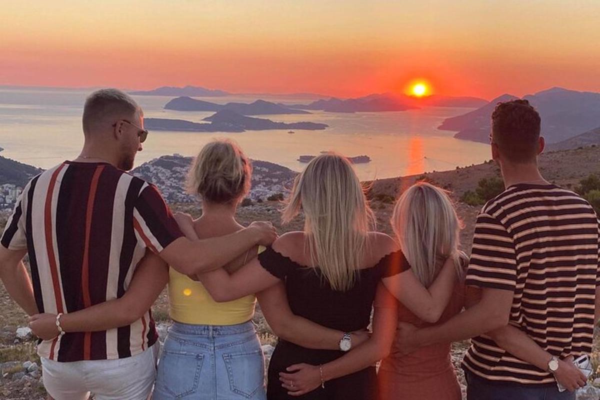 en gruppe mennesker som står foran en solnedgang