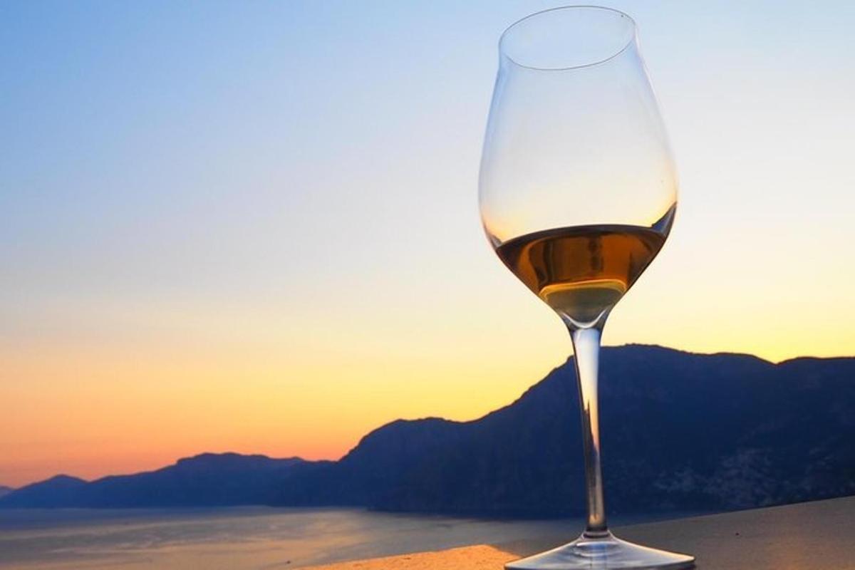 et glass vin som står på et bord med solnedgangen