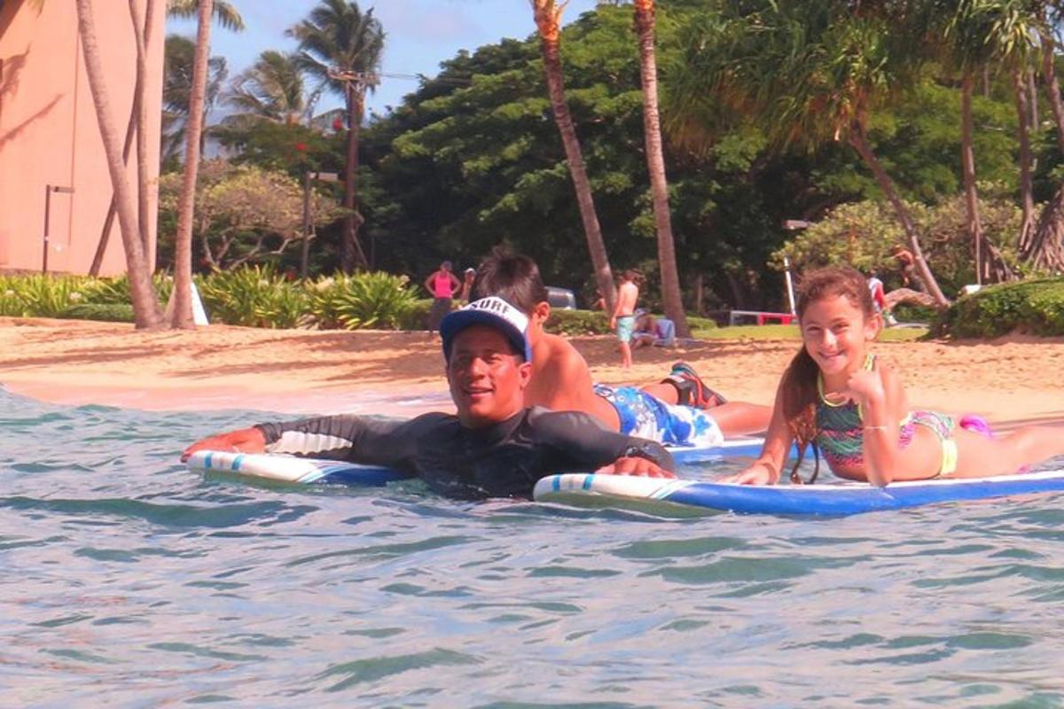 a man and a girl laying on surfboards in the water