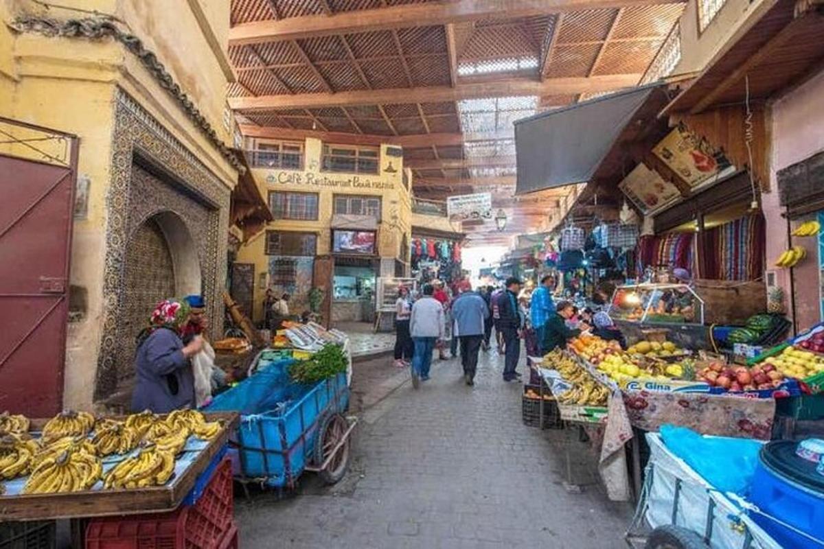 um grupo de pessoas caminhando por um mercado com frutas e vegetais