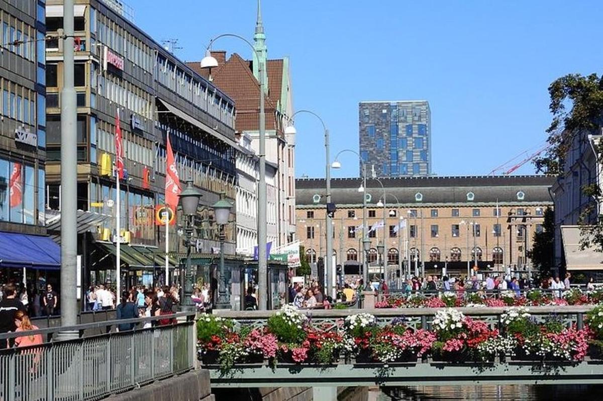 a busy city street with people and buildings and flowers