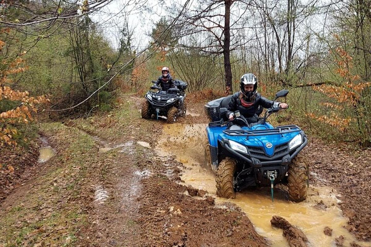 two people riding atvs on a muddy trail