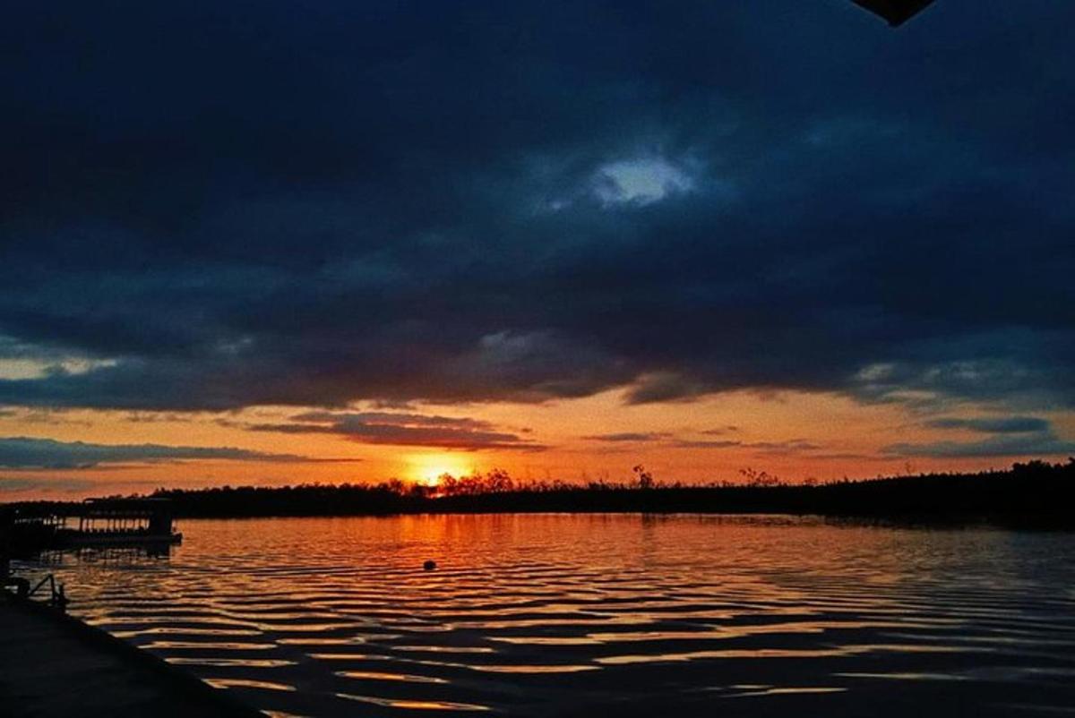 Una puesta de sol sobre un cuerpo de agua con la puesta del sol
