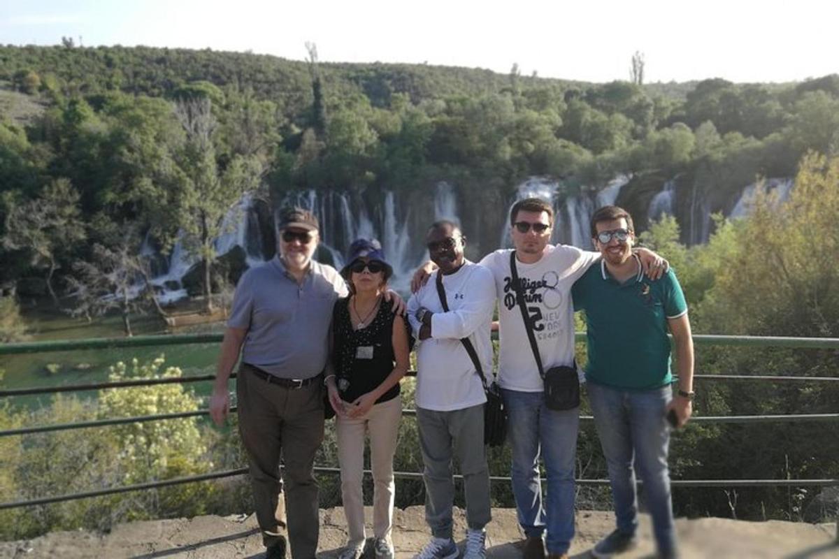 a group of people posing for a picture in front of a waterfall
