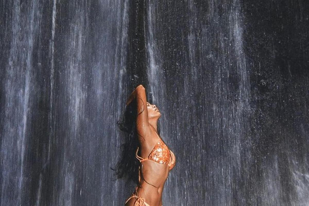 a woman is standing in front of a waterfall