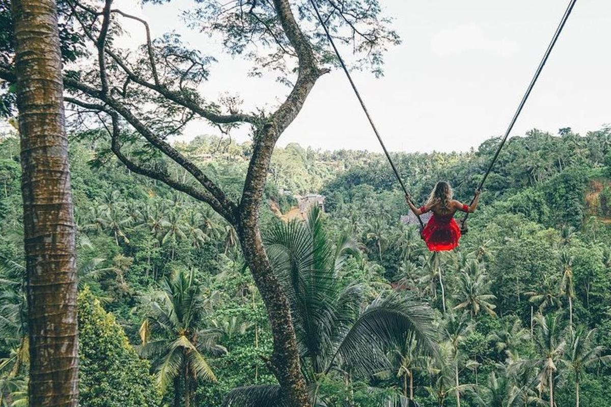 una dona amb un vestit vermell balancejant-se en una tirolina a la selva