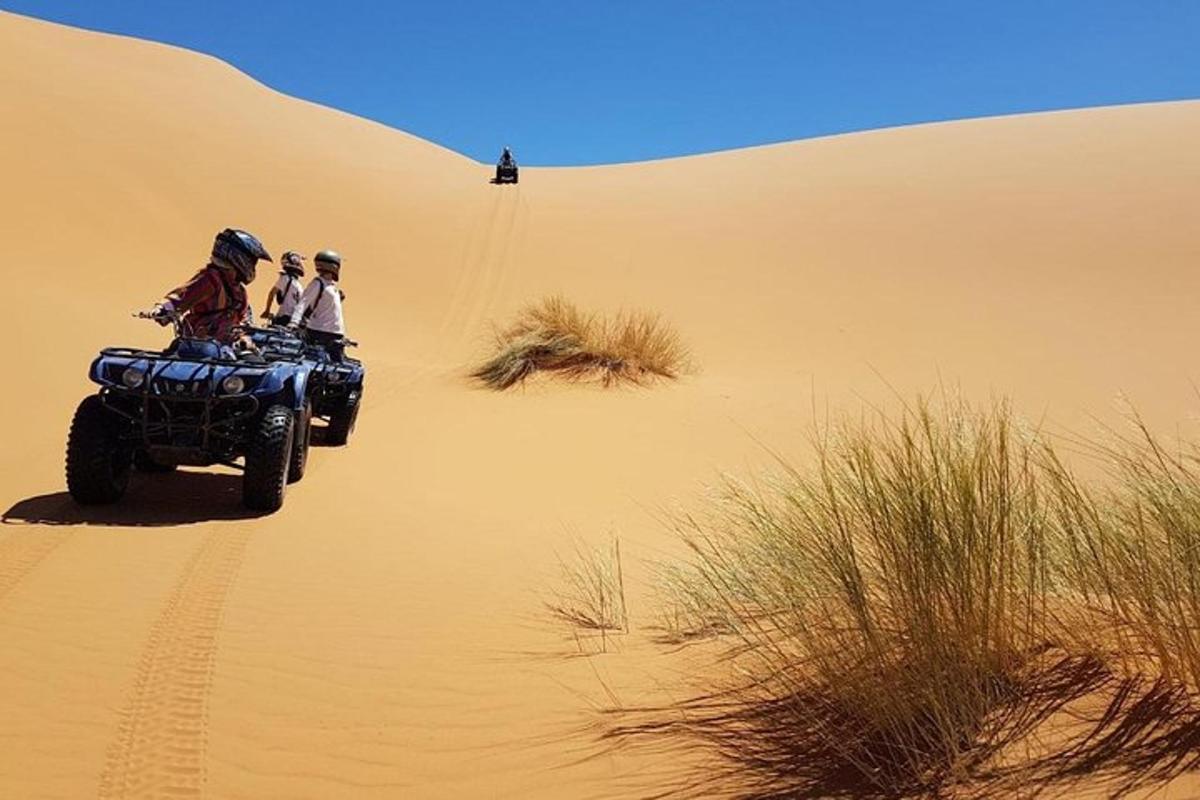 two people riding on a quad bike in the desert