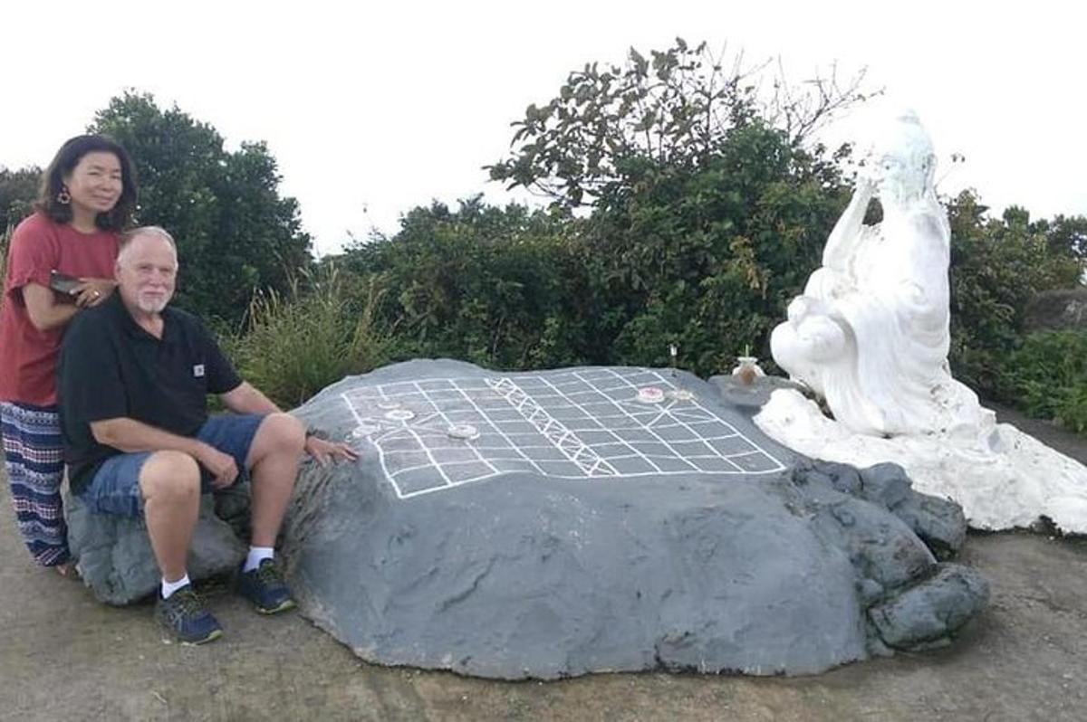 un home i una dona asseguts en una roca al costat d'una estàtua