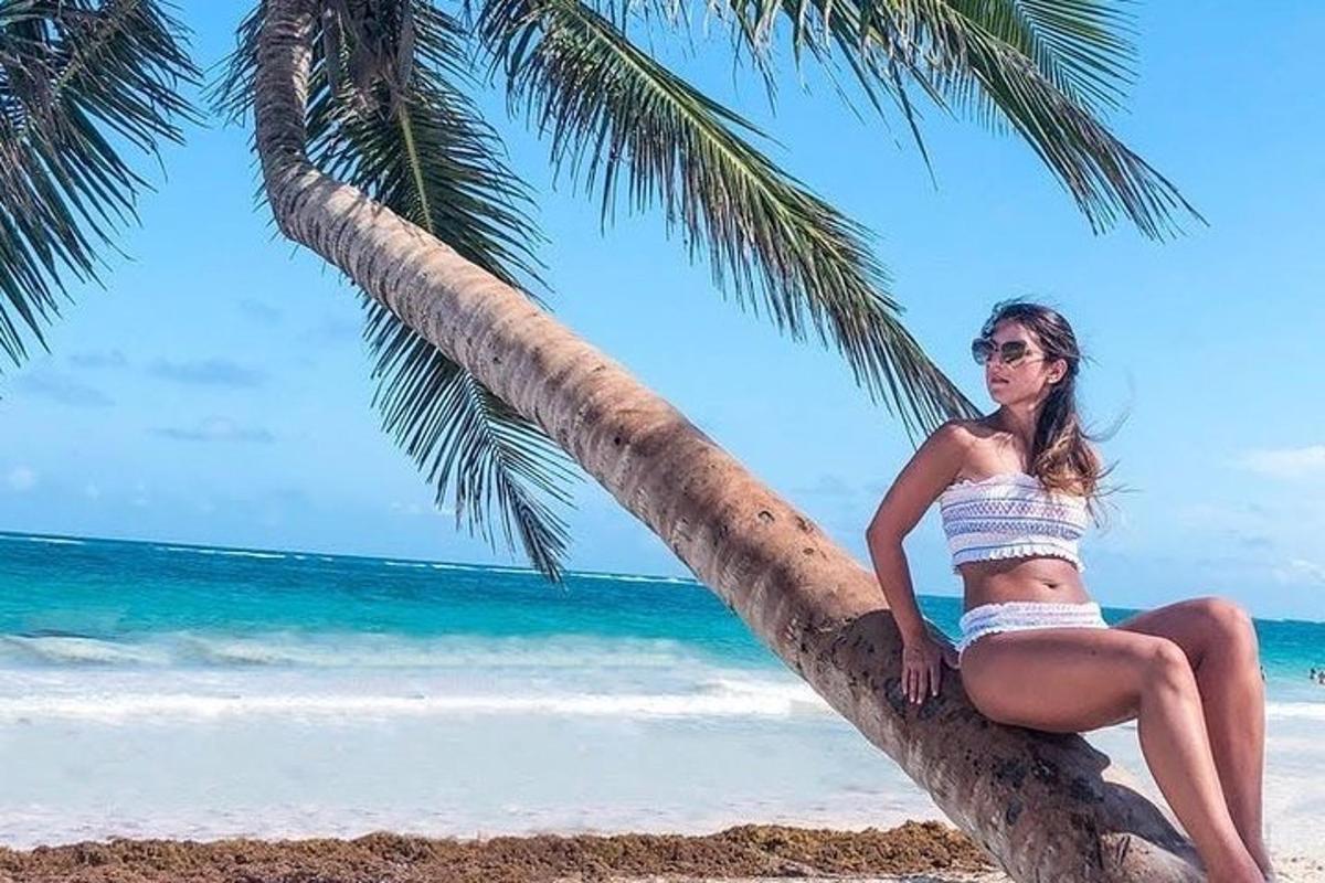 a woman sitting on a palm tree on the beach