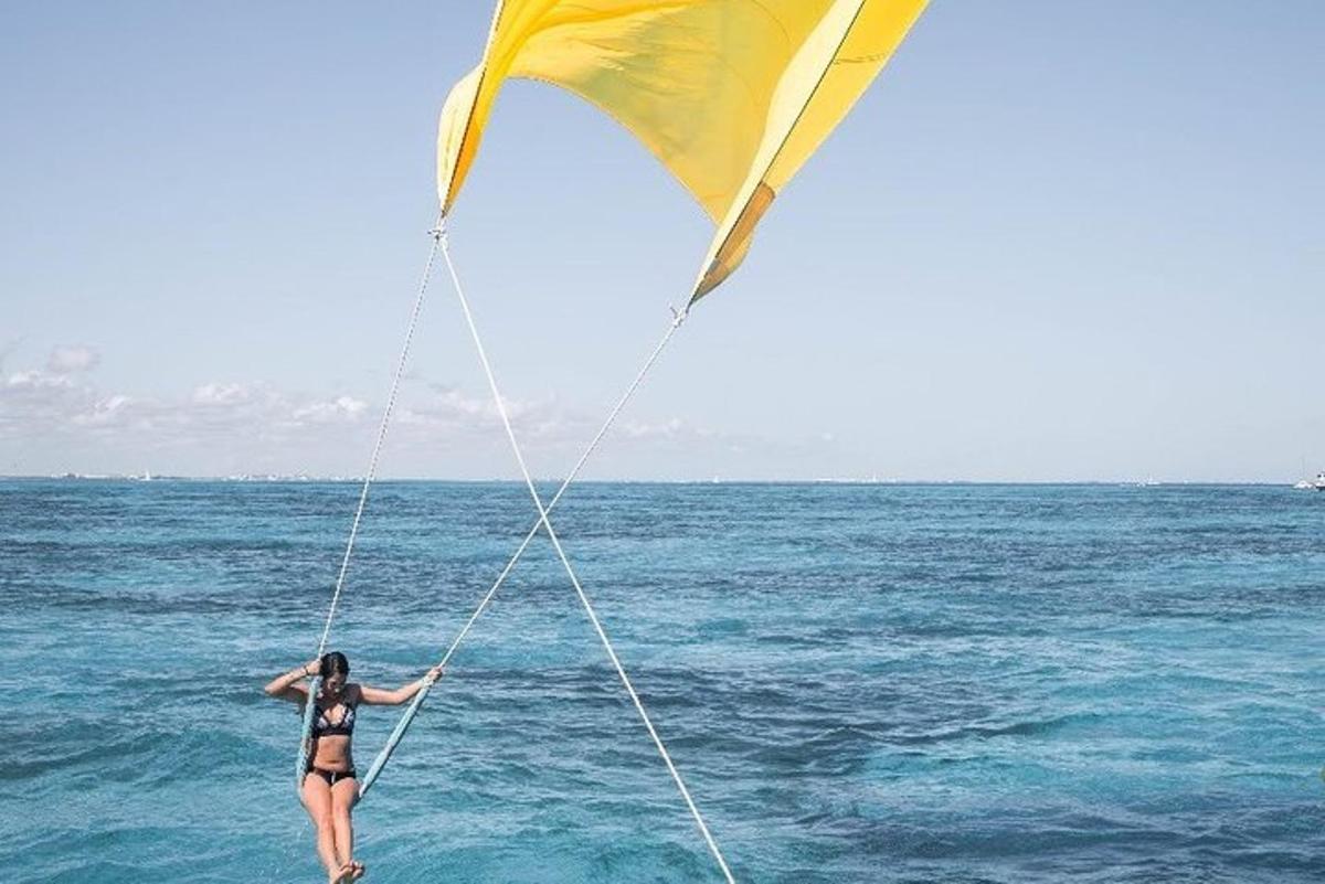 a woman standing in the ocean holding onto a kite