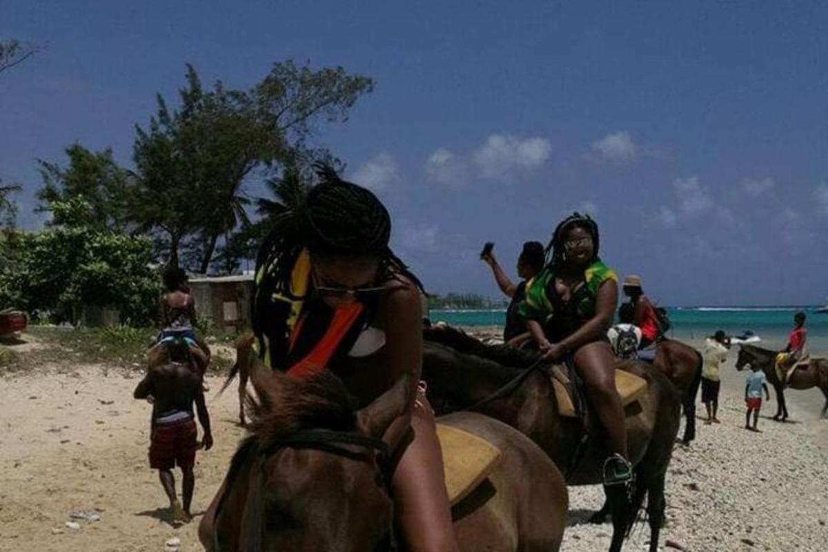 sekumpulan orang menunggang kuda di pantai