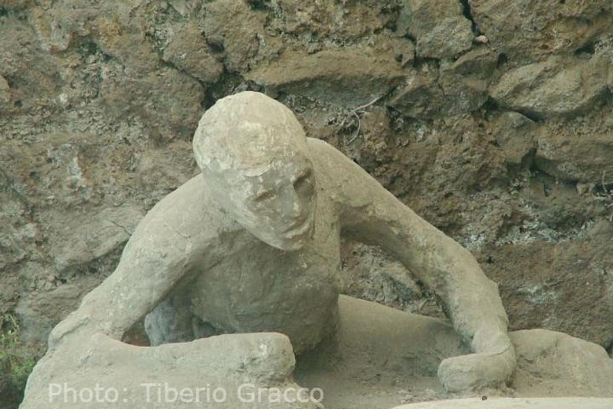 uma estátua de um menino sentado em uma rocha