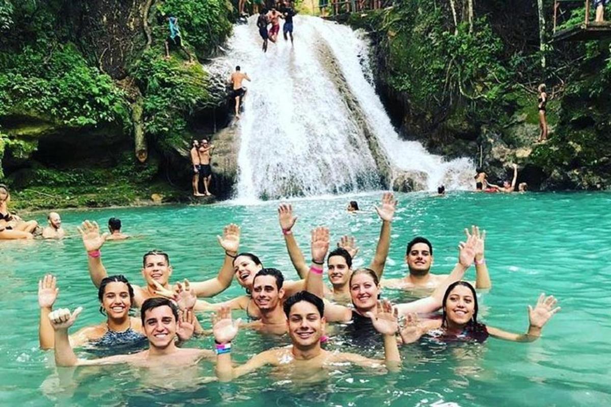a group of people swimming in a pool in front of a waterfall