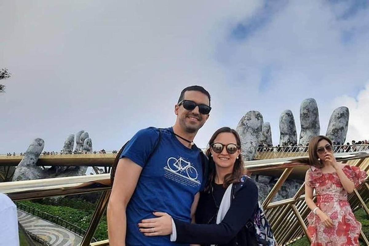 Ένας άντρας και μια γυναίκα ποζάρουν για μια φωτογραφία μπροστά σε μια γέφυρα