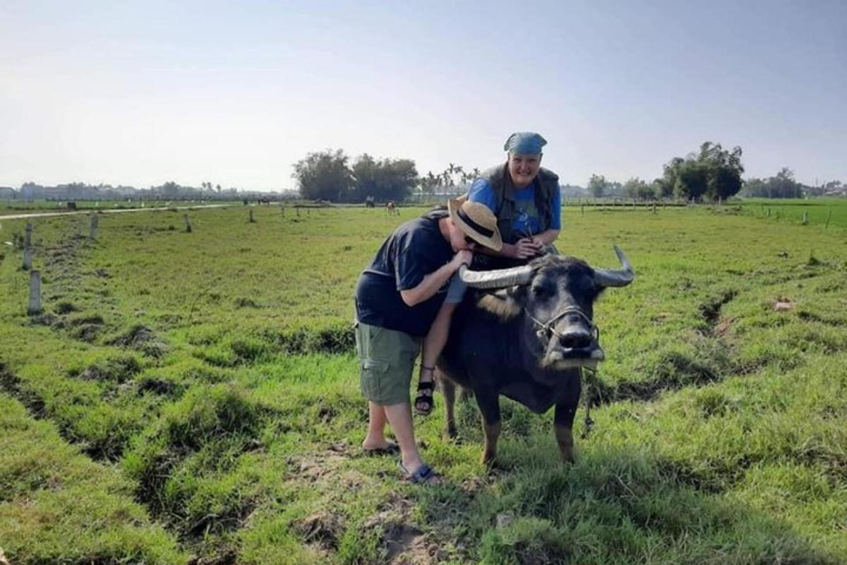 dua pria berdiri di samping seekor sapi di ladang