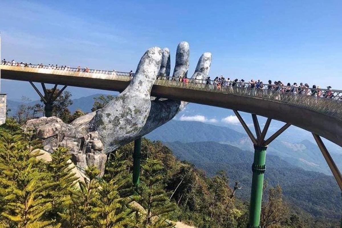 un folto gruppo di persone che attraversa un ponte con una grande mano sul ponte