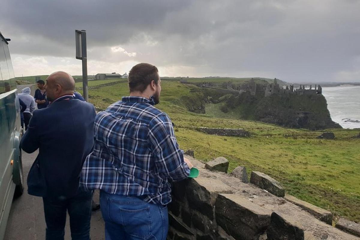 two men looking over a stone wall at the ocean