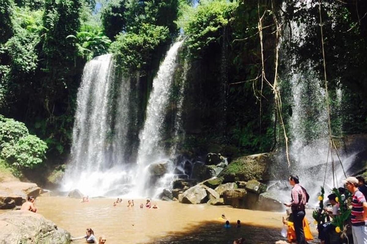 a group of people in the water at a waterfall