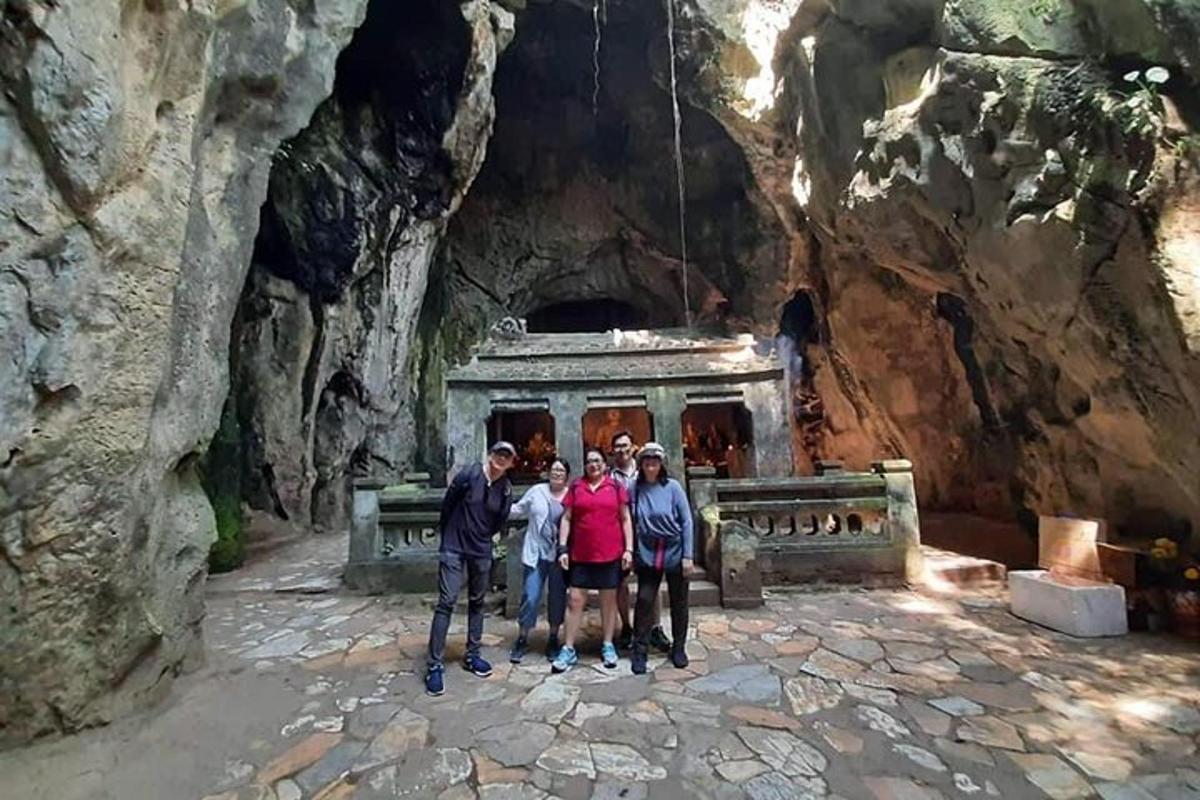 Un grupo de personas de pie frente a una cueva.