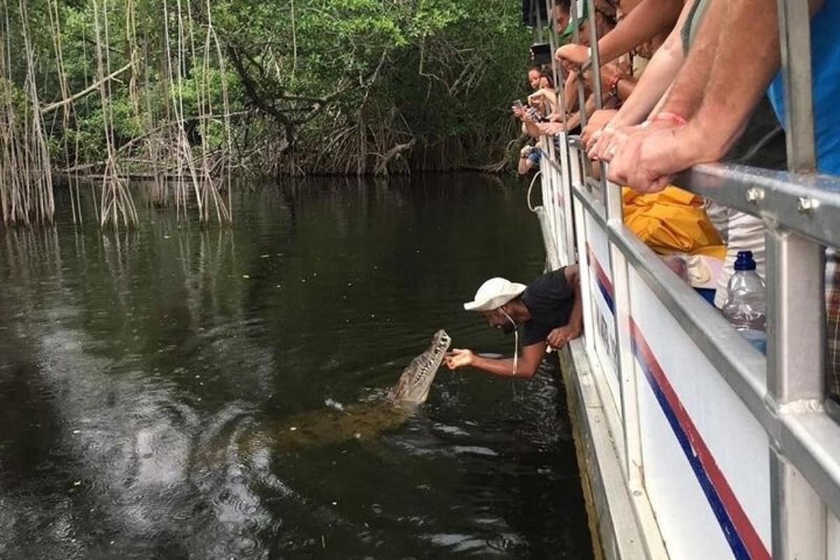 um homem segurando um crocodilo na água em um barco